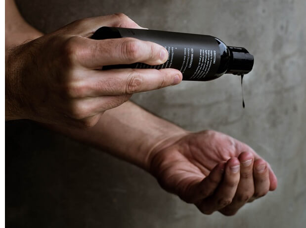 man in shower pouring shampoo into hand